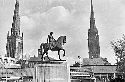 Lady Godiva (died between 1066 and 1086), in Old English Godgifu, was a late Anglo-Saxon noblewoman who is relatively well documented as the wife of Leofric, Earl of Mercia, and a patron of various churches and monasteries. According to the typical version of the story, Lady Godiva took pity on the people of Coventry, who were suffering grievously under her husband's oppressive taxation. Lady Godiva appealed again and again to her husband, who obstinately refused to lower the taxes. At last, weary of her repeated requests, he said he would grant her request if she would strip naked and ride on a horse through the streets of the town. Lady Godiva took him at his word, and after issuing a proclamation that all persons should stay indoors and shut their windows, she rode through the town, clothed only in her long hair. Just one person in the town, a tailor ever afterwards known as 'Peeping Tom', disobeyed her proclamation in what is the most famous instance of voyeurism. In most versions of the story, Tom is struck blind or dead for his transgression. The Coventry Flag, designed by Simon Wyatt,was adopted through a popular vote on 7 December 2018.The design features Lady Godiva, a local heroine, depicted in black on a white pale, symbolising Coventry's history, principles, and its reputation as a city of peace.